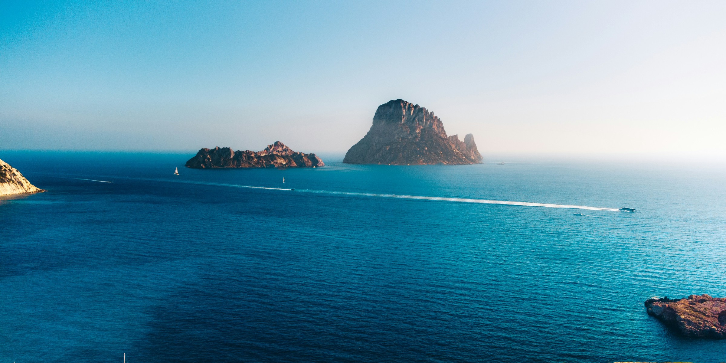 Es Vedrà island off the coast of Ibiza, with yachts on the sea